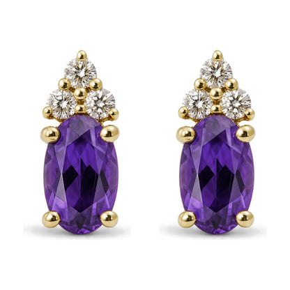 Pair of yellow metal earrings shown in close-up from the front, each featuring an oval purple gemstone with prong setting and a cluster of round white gemstones above.