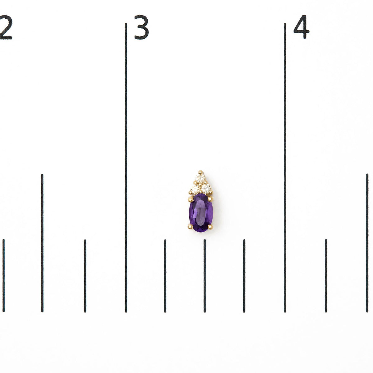 Close-up front view of a single yellow metal earring displayed on a scale, featuring an oval-shaped purple gemstone below a cluster of round white gemstones in prong settings.