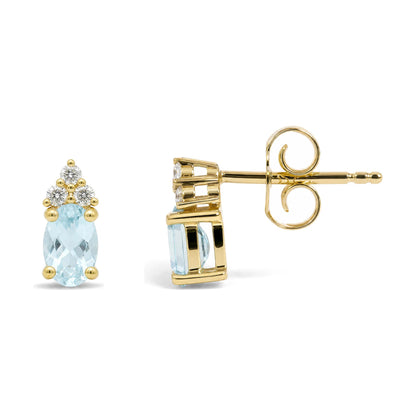 Close-up front and side view of a pair of yellow metal stud earrings featuring oval blue gemstones with multiple small round white gemstones above, all in prong settings.