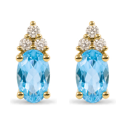 Close-up front view of a pair of yellow metal earrings featuring oval blue gemstones and round white gemstones in prong settings.