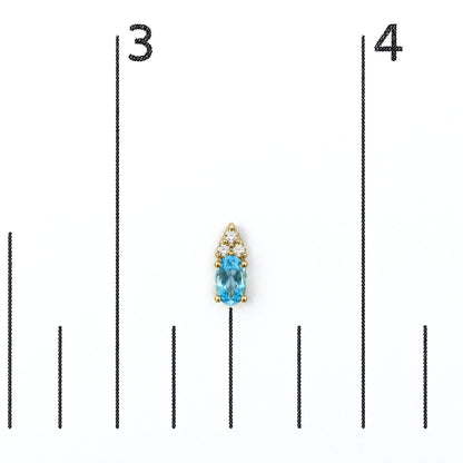 Close-up front view of a yellow metal earring with an oval blue gemstone at the bottom and a cluster of round white gemstones above, shown on a measurement scale.