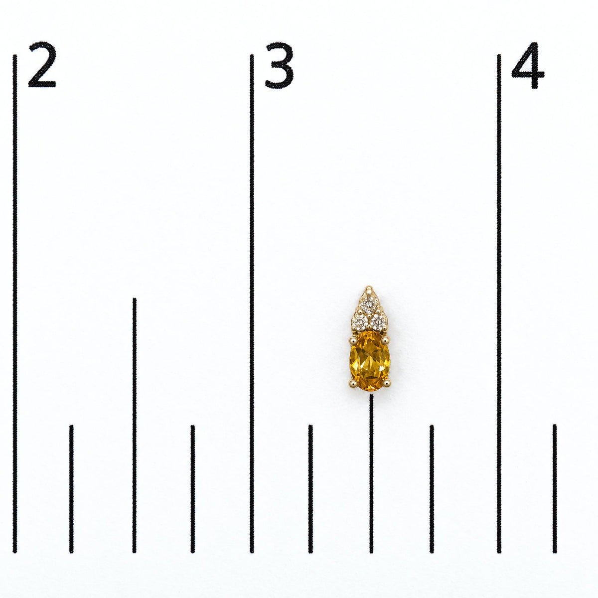 Close-up front view of a yellow metal earring shown on a scale, featuring an oval yellow gemstone with a prong setting below six round white gemstones also in prong settings.