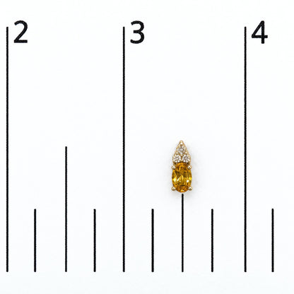Close-up front view of a yellow metal earring shown on a scale, featuring an oval yellow gemstone with a prong setting below six round white gemstones also in prong settings.