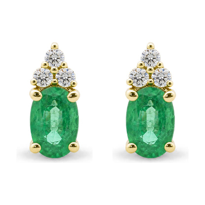 Pair of yellow metal earrings shown in a close-up front view, each featuring an oval green gemstone held by prongs with a cluster of round white gemstones above.