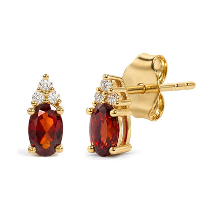 Close-up front and side view of yellow metal stud earrings with oval red gemstones surrounded by round white gemstones in prong settings.