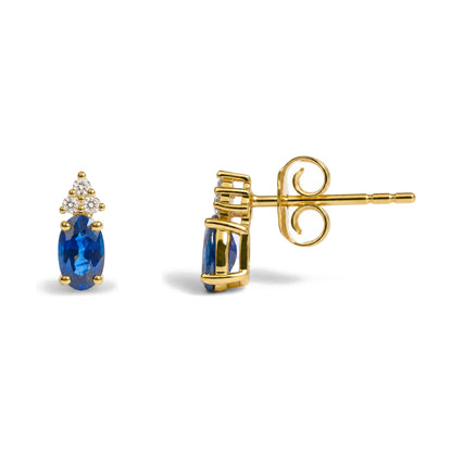 Close-up side angle of a yellow metal earring featuring an oval blue gemstone held by prongs with a cluster of round white gemstones above, also in prong settings, shown on a white background.