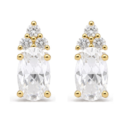 Close-up front view of a pair of yellow metal earrings featuring an oval white gemstone set with prongs, accented above by three round white gemstones in prong settings.