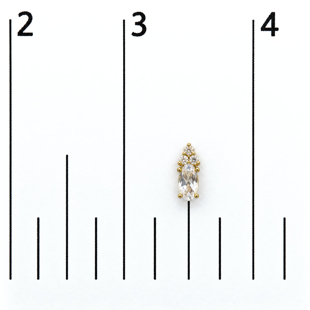 Close-up front angle of a single yellow metal earring shown on a scale, featuring an oval white gemstone at the center surrounded by several small round white gemstones in a prong setting.