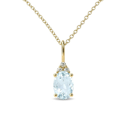 Close-up front angle of a yellow metal necklace with an oval blue gemstone pendant surrounded by three small round white gemstones above it.