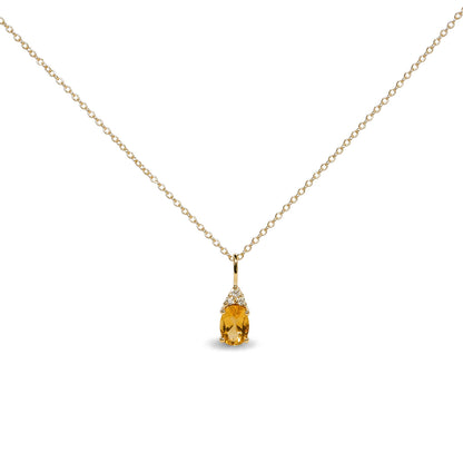 Close-up front view of a yellow metal necklace with an oval yellow gemstone pendant accented by three round white gemstones in prong settings.