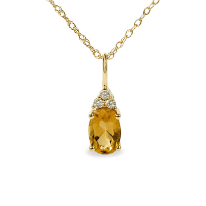Close-up front angle of a yellow metal necklace chain with a pendant featuring an oval yellow gemstone and three round white gemstones above it in prong settings.