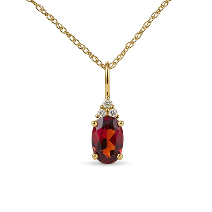 Close-up front view of a yellow metal necklace with a pendant featuring an oval-shaped red gemstone and three round white gemstones above it, all in prong settings.