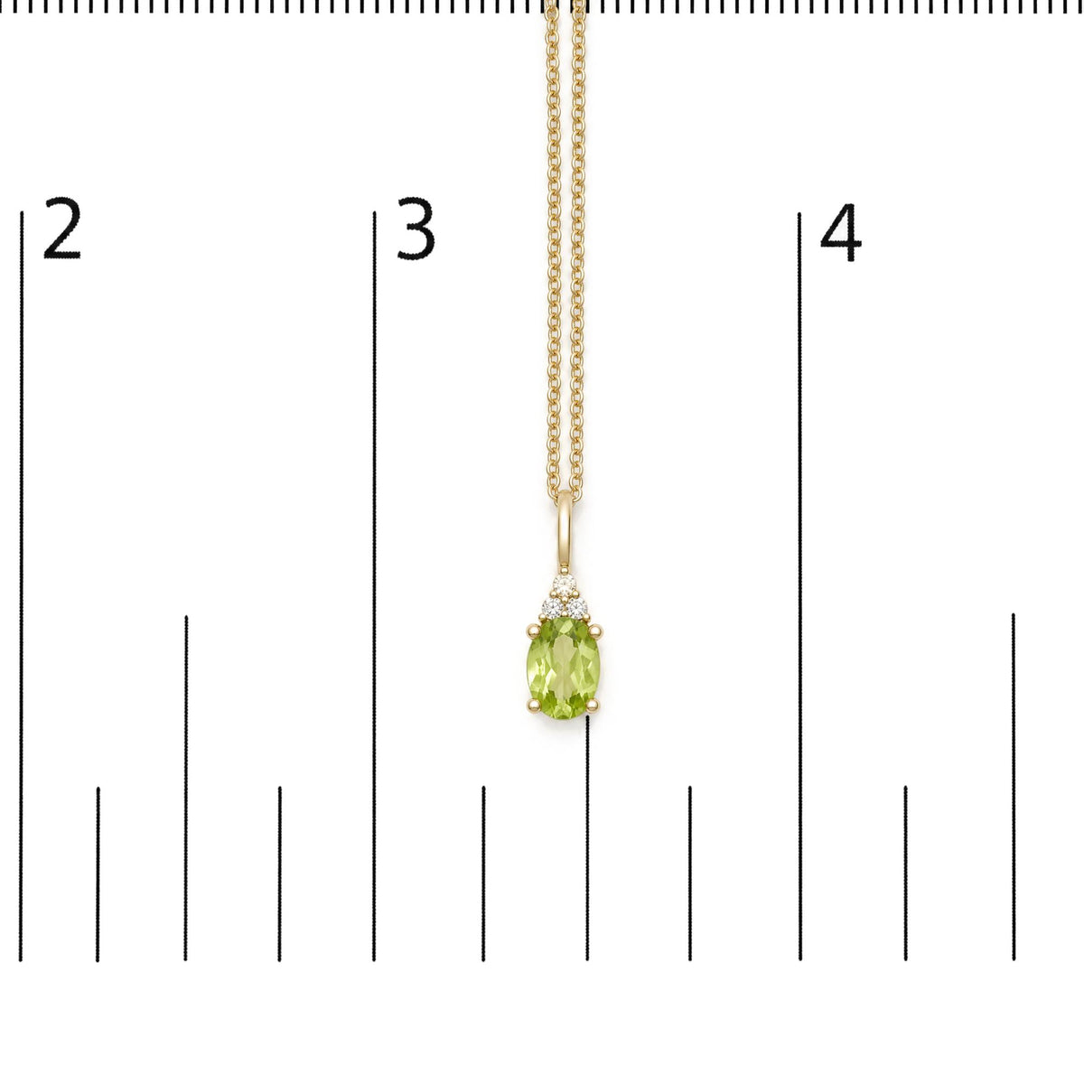 Close-up front view of a yellow metal necklace with an oval green gemstone and three round white gemstones, shown on a scale.