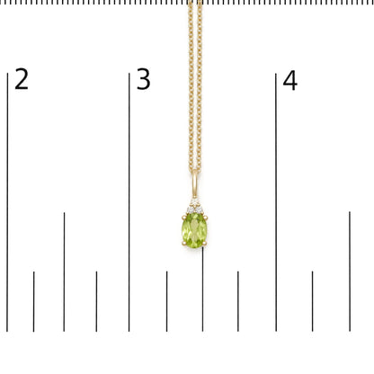 Close-up front view of a yellow metal necklace with an oval green gemstone and three round white gemstones, shown on a scale.