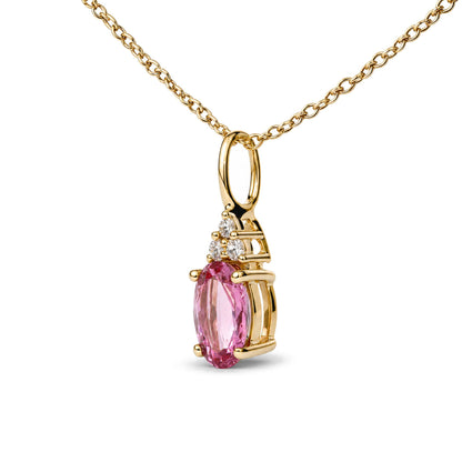 Close-up front angle of a yellow metal necklace with a pendant featuring a large oval pink gemstone and three small round white gemstones in prong settings.