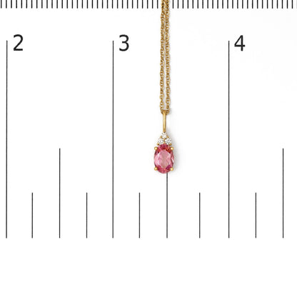 Close-up front view of a yellow necklace with a pendant featuring an oval pink gemstone and three round white gemstones, shown on a scale.