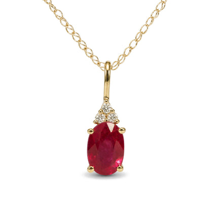 Close-up front view of a yellow metal necklace with oval-shaped red gemstone pendant accented by round white gemstones in prong settings.