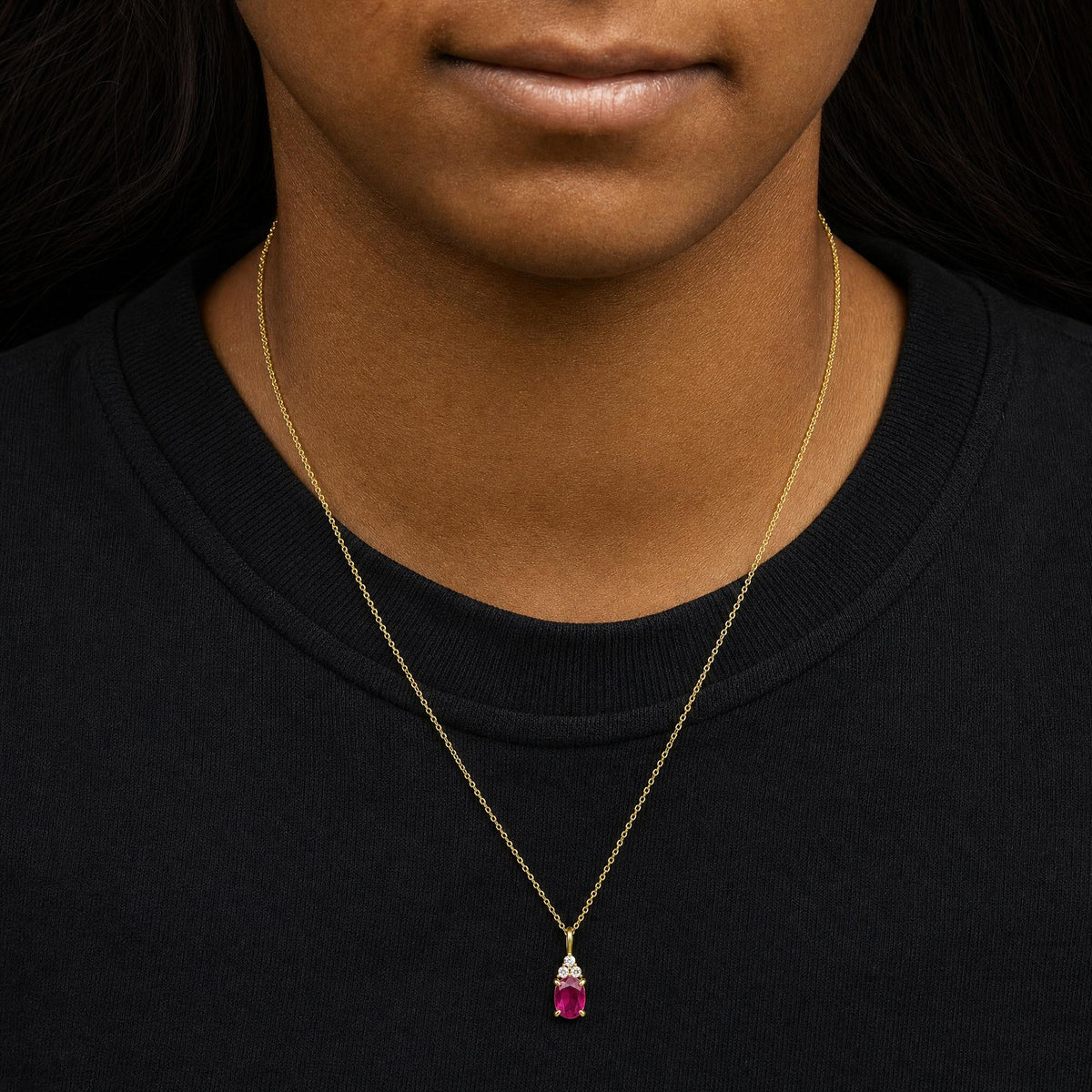 Yellow necklace with a pendant featuring an oval red gemstone and three round white gemstones in prong settings, shown worn on a model from a front angle.