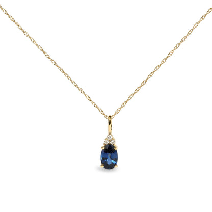 Yellow metal necklace with a delicate chain, featuring a pendant with an oval-shaped blue gemstone framed by three round white gemstones in prong settings, shown in a close-up front view.