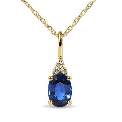 Close-up front view of a yellow metal necklace pendant featuring an oval blue gemstone set below three round white gemstones in prong settings, hanging from a twisted linked chain.