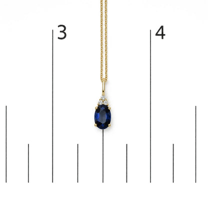 Yellow necklace with a blue oval gemstone pendant surrounded by three round white gemstones in prong settings, shown on a scale from a front angle.