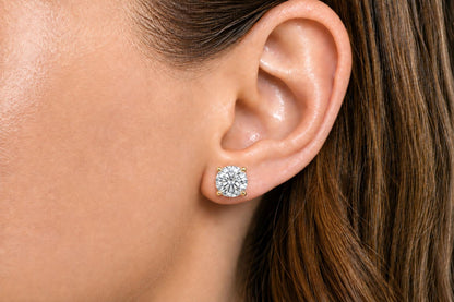 Close-up side angle of a model wearing a yellow metal stud earring with a round white gemstone in a four-prong setting.