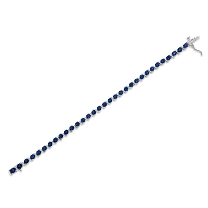 White metal bracelet shown flat at a slight diagonal angle, set with round blue gemstones in prong settings along its length.