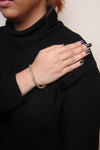 Yellow bracelet with round white gemstones in prong settings, worn on a model's wrist, shot from the side.