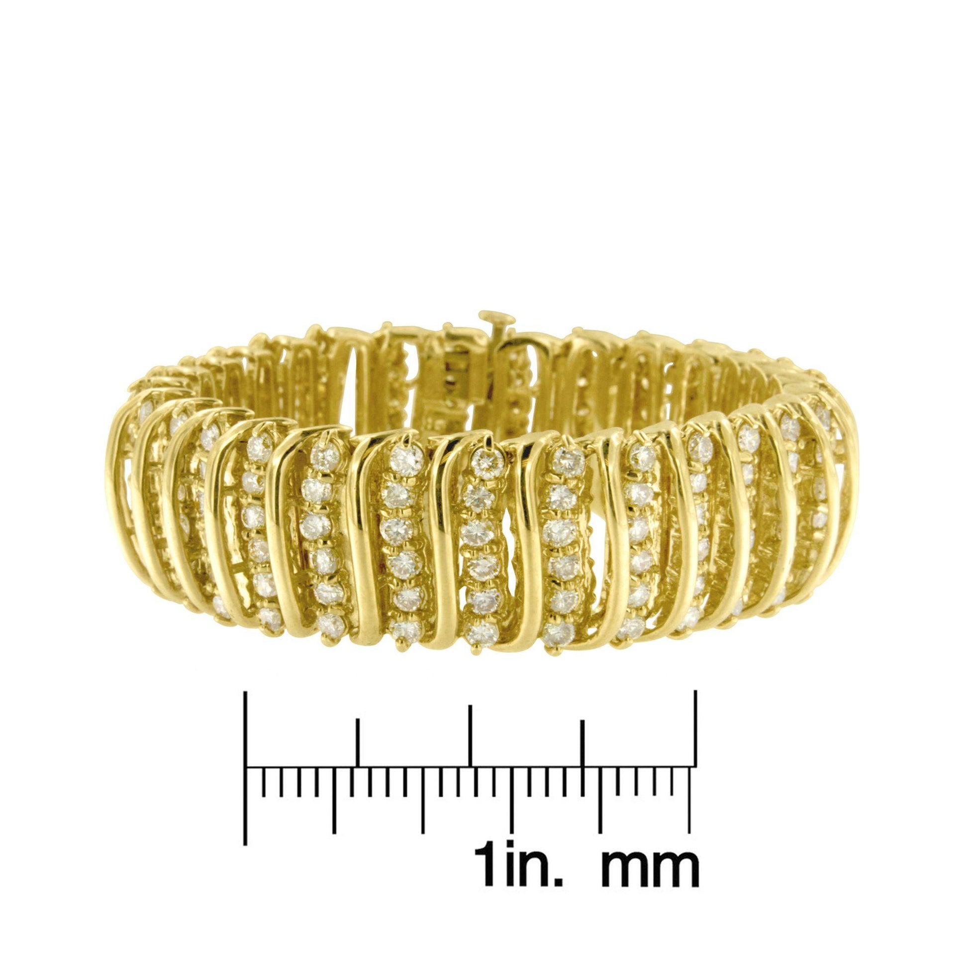 Yellow metal bracelet with multiple rows of round white gemstones in prong settings, shown from the front on a ruler for size reference.