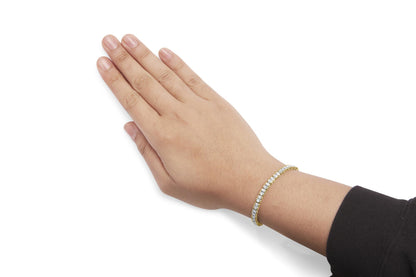 Yellow bracelet with round white gemstones in prong setting, shown on a model's wrist at an angled top view.
