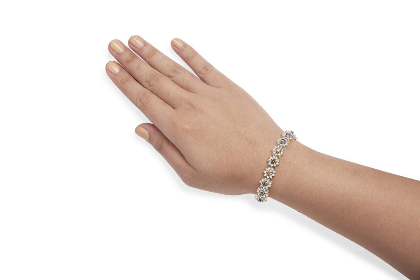 Yellow metal bracelet with alternating champagne and white round gemstones in prong settings, shown on a model's wrist, shot from a top angle.