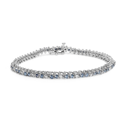 White metal bracelet with alternating white and blue round gemstones in 3-prong settings, shown from a front angle on a white background.