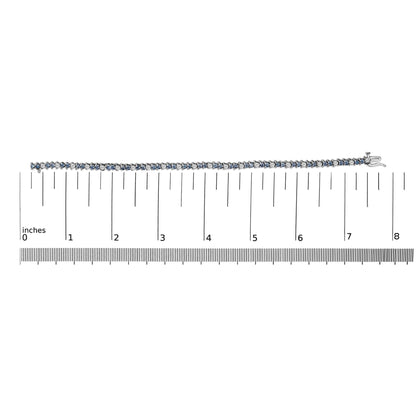 White metal bracelet with alternating white and blue round gemstones in three-prong settings, shown lying flat on a ruler for scale, top-down view.