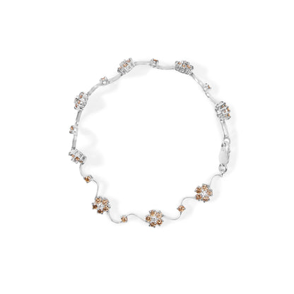 White metal bracelet with round white and champagne gemstones in prong settings, arranged in clusters and linked by thin metal strands, shown from a top-down angle.