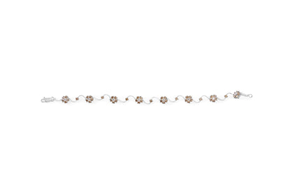 White metal bracelet with alternating clusters of white and champagne round gemstones in prong settings, photographed flat from the front.