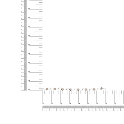 White metal bracelet with alternating clusters of white and champagne round gemstones in prong settings, laid flat on intersecting rulers for size reference, top-down angle.