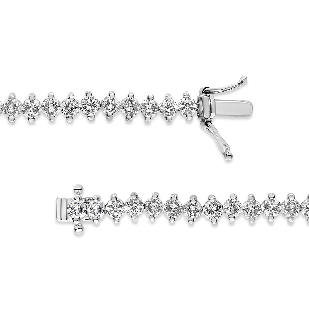 Close-up top view of a white metal bracelet with round white gemstones in a 2-prong setting and a clasp closure.