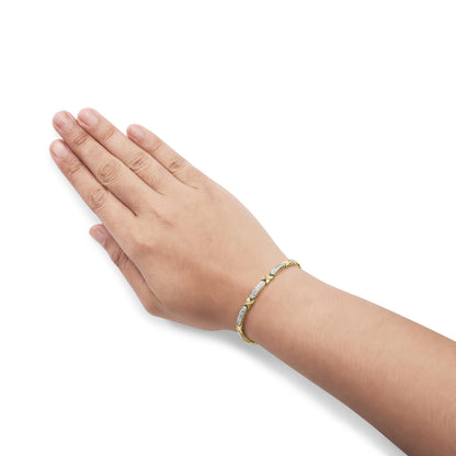 Yellow bracelet with alternating sections of white gemstones in prong settings, shown on model's wrist angled top-down.