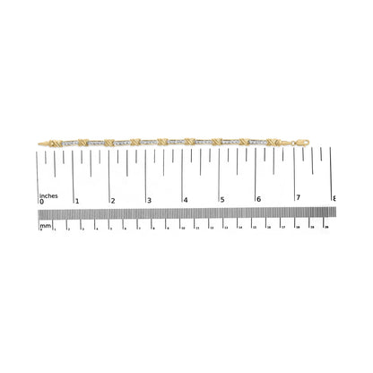 Yellow metal bracelet with alternating sections of white round gemstones in prong settings and solid links, shown flat on a ruler for size reference, top-down angle.