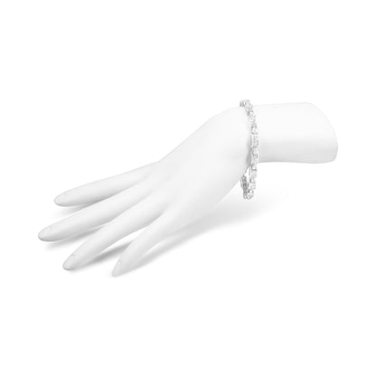 White metal bracelet with princess shape white gemstones in an invisible setting, shown worn on a model's hand angled to the side.