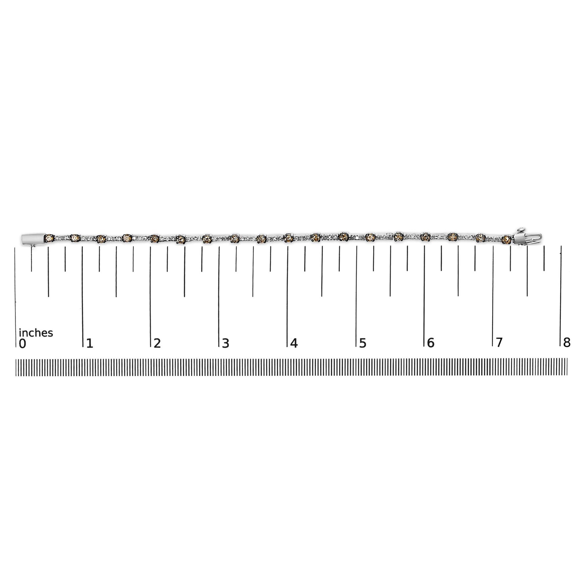 White metal bracelet with alternating white and champagne round gemstones in prong settings, laid flat on a ruler for size reference, top-down view.