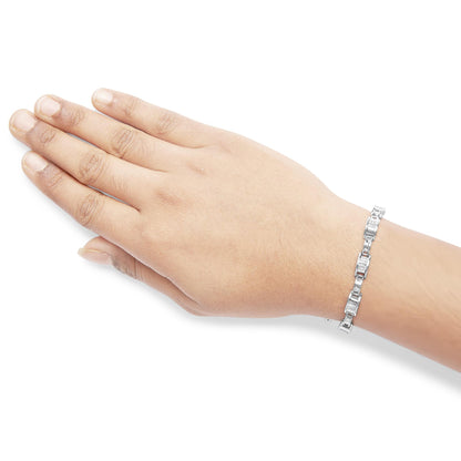 Close-up side angle of a hand wearing a white metal bracelet with princess-shaped white gemstones in an invisible setting.