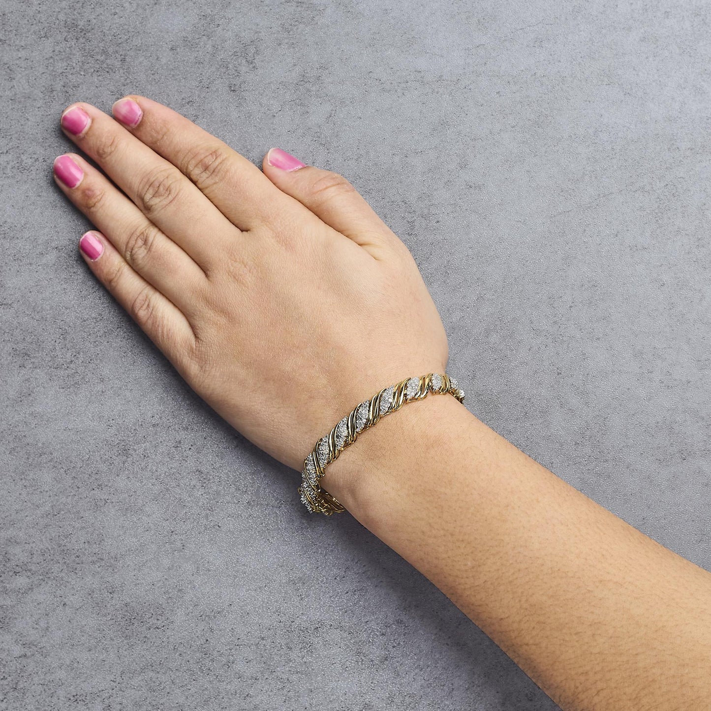Yellow bracelet with round white gemstones in prong setting, shown worn on a model's wrist, angled top-down view.