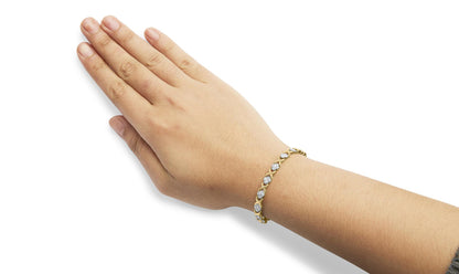 Yellow bracelet with round white gemstones in pave setting, shown on a wrist at an angled top-down view.