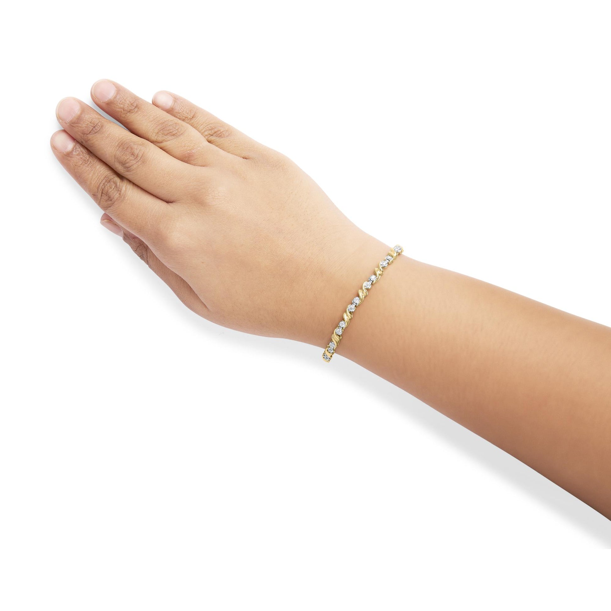 Bracelet with round white gemstones in miracle setting on yellow metal, shown on wrist of a model, side angle.