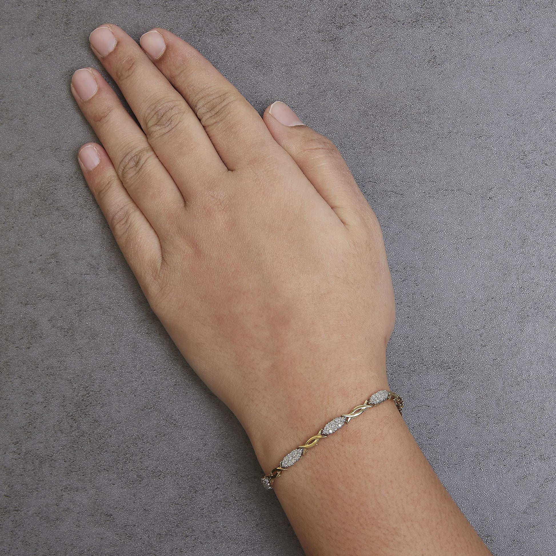 Yellow bracelet with white round gemstones in prong settings, shown on a model's wrist from a top-down angle.