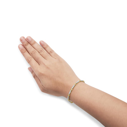 Bracelet with alternating yellow and white metal links and prong-set round white gemstones, worn on a model's wrist, shot from the side angle.