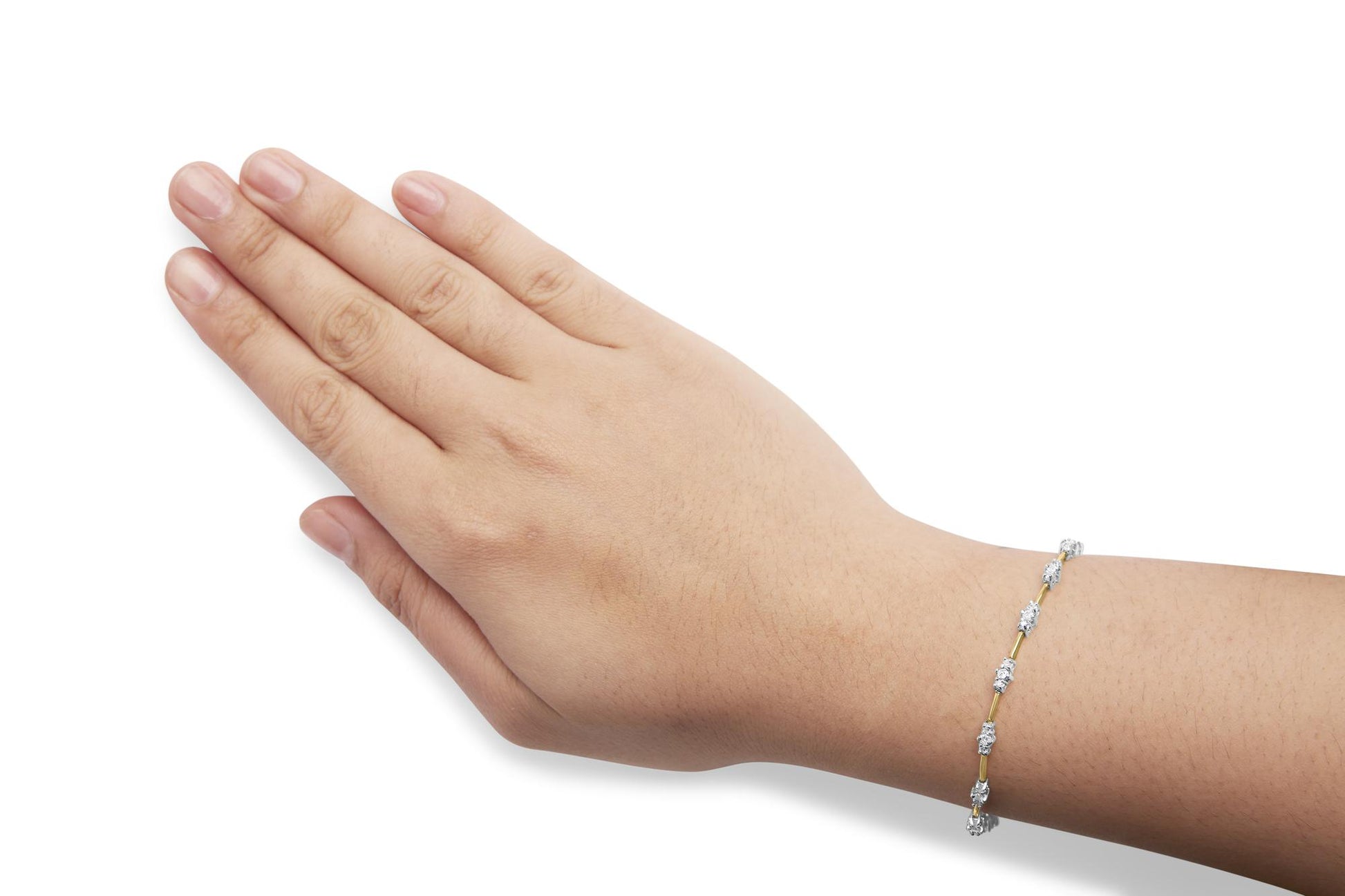 Close-up side view of a yellow metal bracelet with white round gemstones in prong settings, worn on a model's wrist.