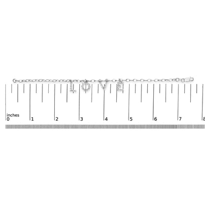 White metal bracelet with charms spelling 'LOVE' set with round white gemstones, shown flat on a ruler for size reference, top-down angle.