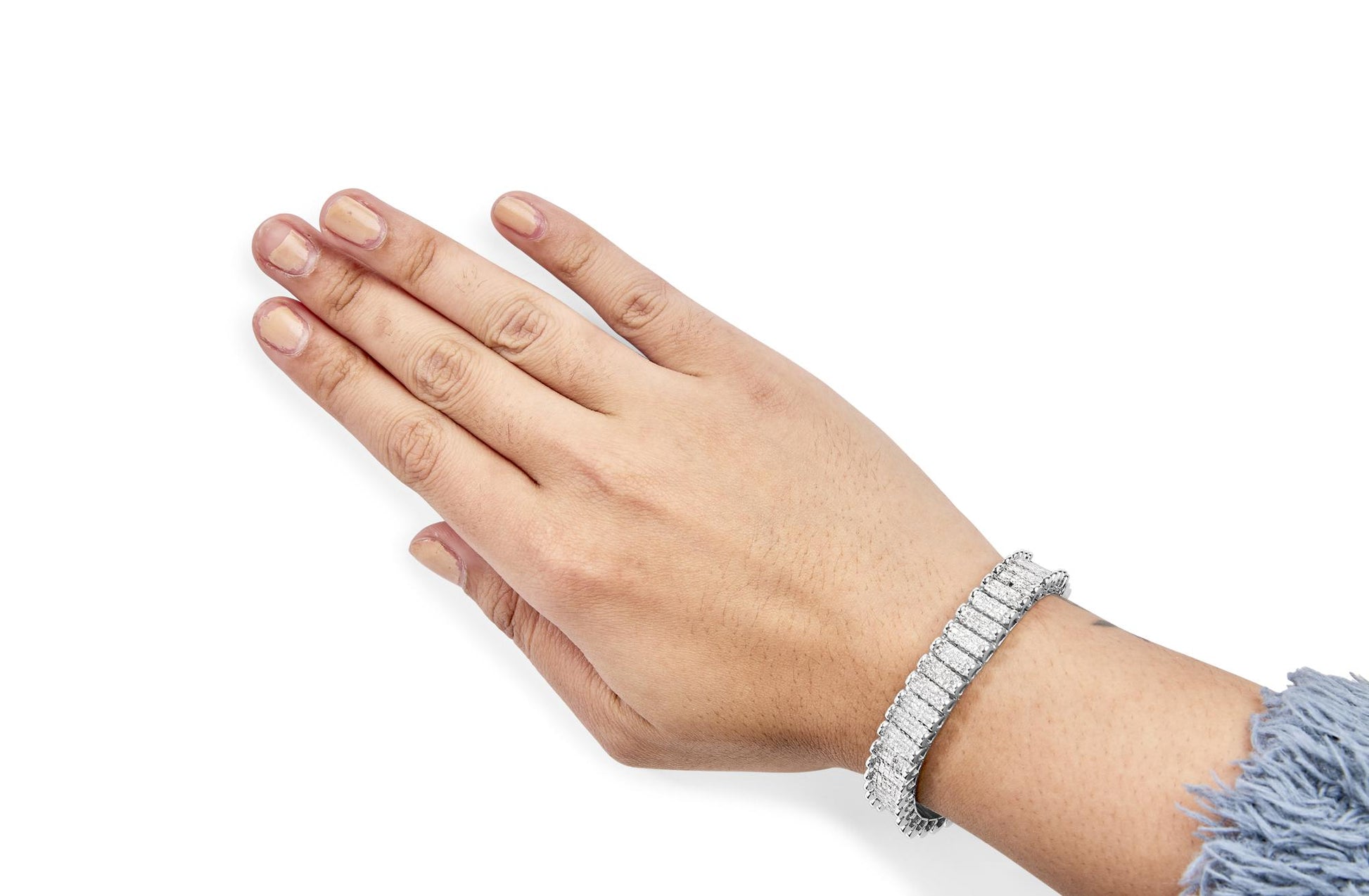 Close-up of a white bracelet with rectangular white gemstones in an invisible setting, worn on a model's wrist shown from above.